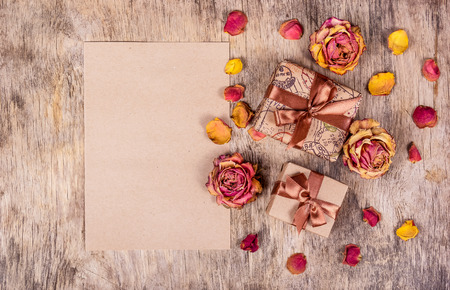 Gift boxes, message and roses on wooden background. Dry flowers, dried roses.の写真素材