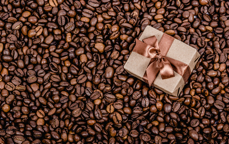 Gift box with ribbon on coffee background.  Roasted coffee beans background. Copy spaceの写真素材