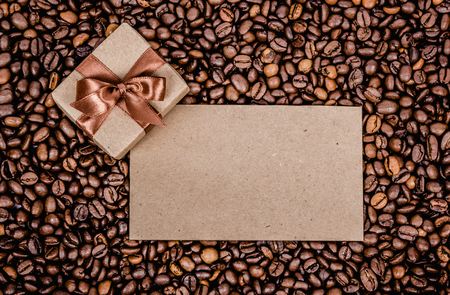 Roasted coffee beans background. Gift box, letter and coffee. Copy space. Scrapbook. Top viewの写真素材