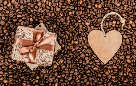 Gift box with bow and Valentine. Gift box with ribbon and wooden heart. Coffee background and gift.の写真素材