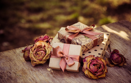 Gift boxes and dry roses. Dried flowers and craft gift box. stack of gifts and dried flowers. Gifts in brown paperの写真素材