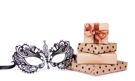Lace mask and gifts. Metal masquerade mask and stack of gifts. Gift boxes on white background. Mask on white backgroundの写真素材