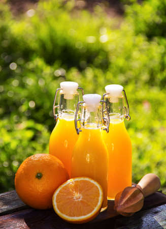 Orange juice and wooden mudler. Orange drink in bottlesの写真素材