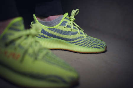 A man wearing Adidas Yeezy Boost 350 v2 Sply semi frozen yellow sport shoes. Krasnoyarsk, Russia - December 26, 2017のeditorial素材