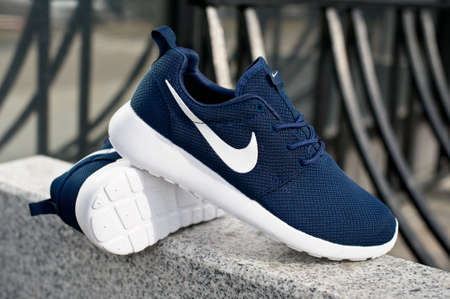 Dark blue Nike Roshe Run running shoes, sneakers, trainers close up view, shot outdoors on grey urban background. Sport and casual footwear concept. Krasnoyarsk, Russia - April 16, 2015のeditorial素材