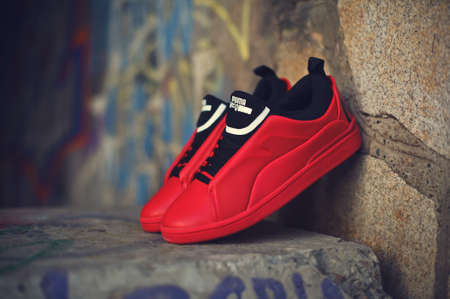 Beautiful red and black sneakers McQ By Alexander McQueen x Puma Brace Lo shot outdoor on colorful abstract background. Close up view of casual sport shoes. Krasnoyarsk, Russia - December 19, 2017のeditorial素材