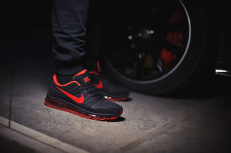 A man wearing Perfect Nike Air Max 2017 sport shoes shot near the Mercedez Benz car on dark...