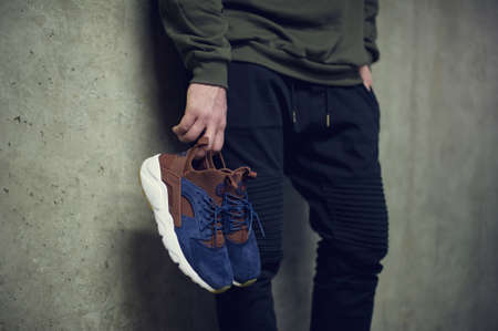 Young man holding blue Nike Air Huarache sport shoes shot on grey background. Nike sneakers, trainers close up view. Sport and casual footwear concept. Krasnoyarsk, Russia - January 10, 2018のeditorial素材