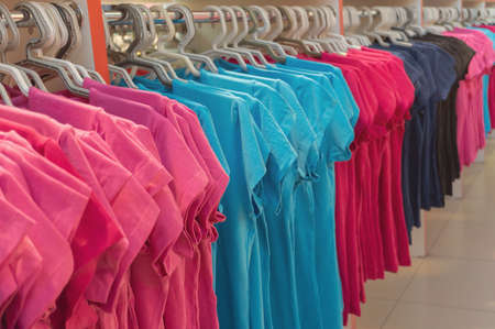 Row of colorful T shirts on hangers. Fashion retail shop display. Clothing business concept.