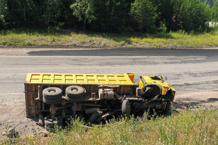 An overturned truck on an highway in an accident. Crashed dump truck on a road.