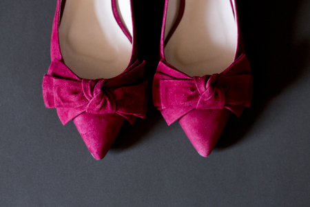 a pair of pink woman shoes with a ribbonand a gray backgroundの写真素材