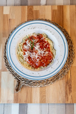 Aerial view of spaghetti bolognese with tomato sauce, meat and cheese in a wooden table ready to eatの写真素材