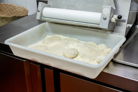 a tray in a restaurant kitchen with raw mass and flour and a roller pin.の写真素材