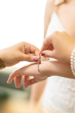 woman hands helping to put a bracelet on a brideの写真素材