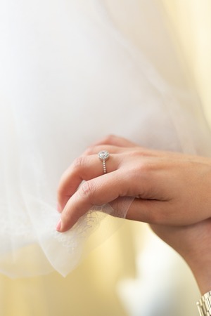 detail of the hand of a bride with an engagement ring holding the fabric of the wedding dress