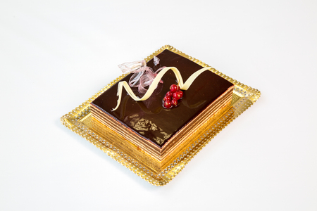 beautiful chocolate cake on a gold tray on white backgroundの写真素材