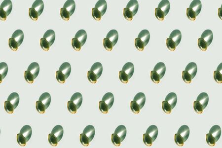 pattern capsules with oils and vitamins on green background. Concept of natural health care.の写真素材