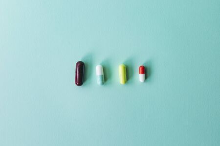 different pills lined up on a blue background. Minimal composition.の写真素材
