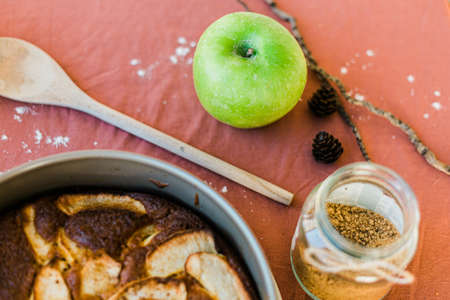 Close up of an apple, sugar and wooden utensil. Ingredients of an apple pie. Pink backgroundの写真素材