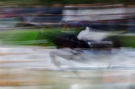 Abstract image with a moving rider and horse at show jumping on blurred background, Herneacova, Romania.の写真素材