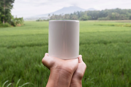 mug mockup. White mug with a background of raung mountains and the rice fields of Banyuwangi Regencyの写真素材