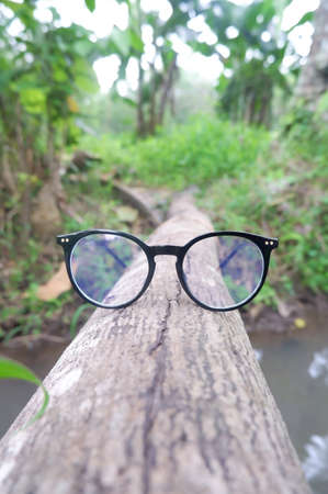 black round glasses on wood with a natural landscape backgroundの写真素材