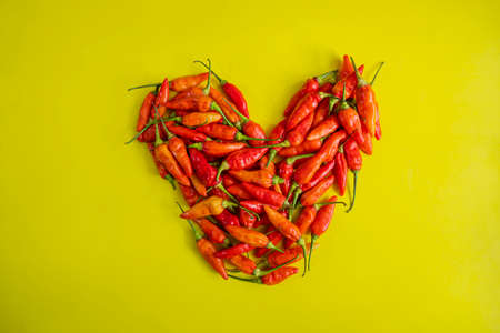 red pepper isolated on a yellow background. little chili peppers forming love  isolated on yellow backgroundの写真素材