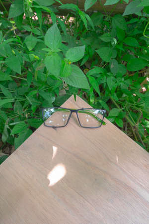 black and green combination square eyeglass frames on old wood. square eyeglass frames in the photo from above with a natural landscape background. square glassesの写真素材