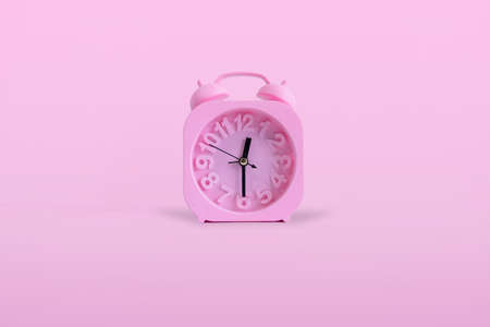 Isolated Pink Alarm Clock On Pastel Pink Background. time is 00:30 o clock.