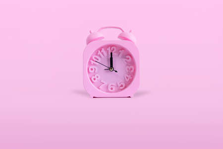 Isolated Pink Alarm Clock On Pastel Pink Background. time is 12:00 o clock.