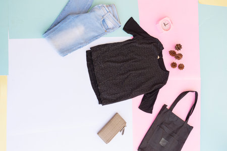 women's shirt, blue jeans, brown purse and black handbag on multi-colored pastel background. fashion...