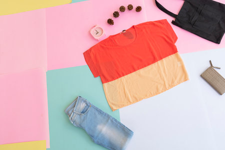 women's shirt, blue jeans, brown purse and black handbag on multi-colored pastel background. fashion...