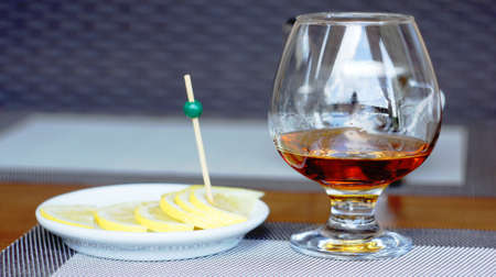 A glass of brandy with slices of lemon, sprinkled with salt and pepper. This is the best remedy for a headache.の写真素材