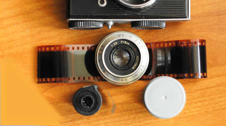Accessories from old film cameras. A still life of accessories from old film camera: camera, lens, film cassette, piece of film, film containerの写真素材