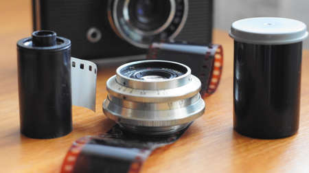 Accessories from old film cameras. A still life of accessories from old film camera: camera, lens, film cassette, piece of film, film containerの写真素材