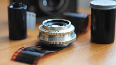 Accessories from old film cameras. A still life of accessories from old film camera: camera, lens, film cassette, piece of film, film containerの写真素材