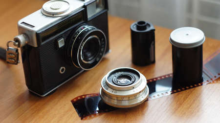 Accessories from old film cameras. A still life of accessories from old film camera: camera, lens, film cassette, piece of film, film containerの写真素材