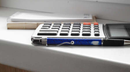 Calculator, pen and paper notepad Counting on the calculator and record the results in a paper.の写真素材