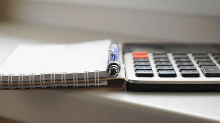 Calculator, pen and paper notepad Counting on the calculator and record the results in a paper.の写真素材