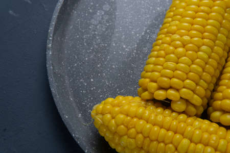 Fresh cooked yellow corn cobs lie on a gray dishの写真素材