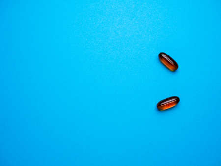 Spilled colored medications and pills on a blue background. Pharmacology and medicine struggle for health. Drug addiction. Treatment of various diseasesの写真素材