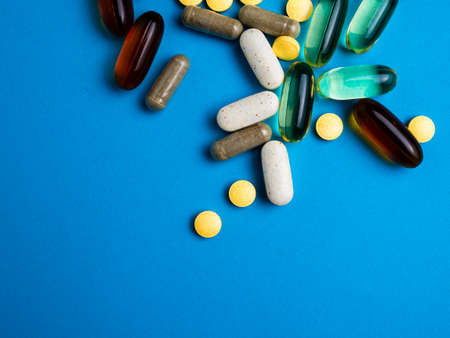 Spilled colored medications and pills on a blue background. Pharmacology and medicine struggle for...