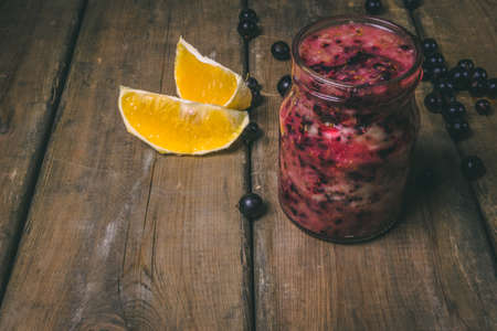 Fruit smoothies made with fresh ingredients on a wooden background. Black currant, orange. Healthy...