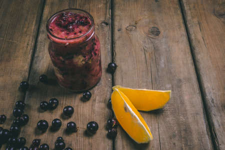 Fruit smoothies made with fresh ingredients on a wooden background. Black currant, orange. Healthy...