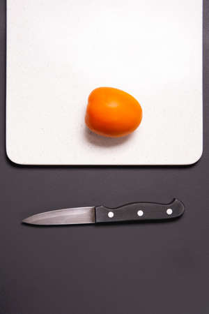 Red tomato and knife on a black background. Kind with a side.の写真素材