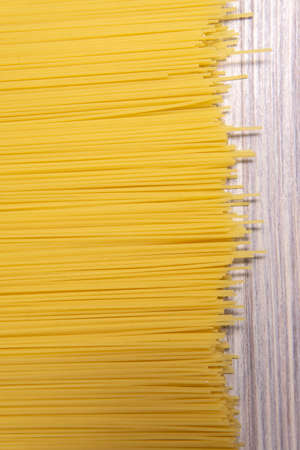raw spaghetti pasta scattered on white wooden table, close-up view from aboveの写真素材