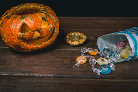 Happy Halloween pumpkin and candies. Trick or treat on a wooden table on a background of old wooden boards. Halloween background. Space for text.の写真素材