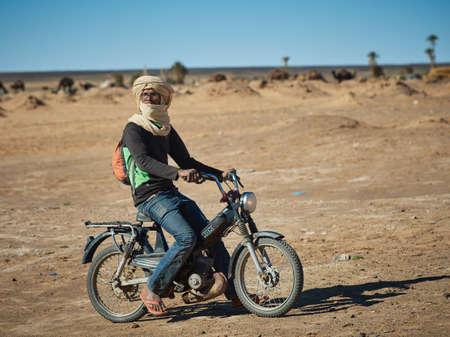 Merzouga, Morocco - December 04, 2018: Berber on a motorcycle, in the middle of the desertのeditorial素材