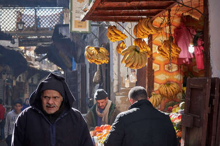 Fez, Morocco - December 07, 2018: Moroccan man walking in the fez medina next to a banana storeのeditorial素材