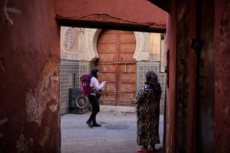Fez, Morocco - December 07, 2018: contrast between a backpacker tourist and a local old lady in the medina of fezのeditorial素材